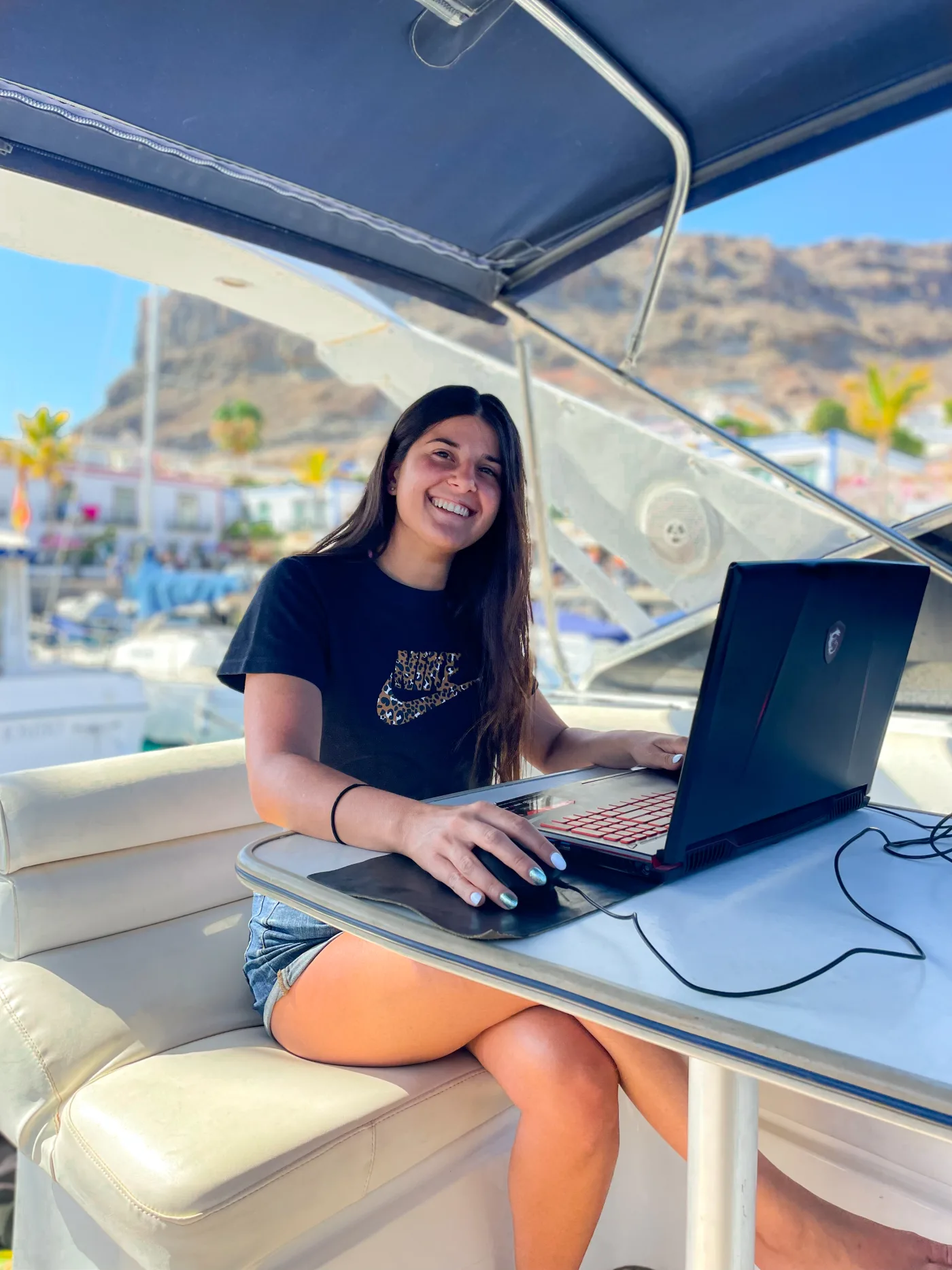 Susanna sorridente al laptop mentre lavora a un progetto 3D, ambiente luminoso outdoor